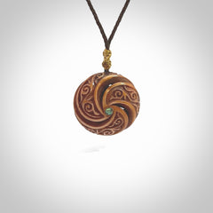 A hand carved and intricate koru pendant made for us by Yuri Terenyi. This is a beautiful little piece and is emblematic of the well known and loved Koru design. It is carved from bone in a hollowed, oval ball shape with decorative design carved into the koru. It is suspended from a chocolate brown cord which is adjustable.