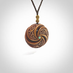 A hand carved and intricate koru pendant made for us by Yuri Terenyi. This is a beautiful little piece and is emblematic of the well known and loved Koru design. It is carved from bone in a hollowed, oval ball shape with decorative design carved into the koru. It is suspended from a chocolate brown cord which is adjustable.