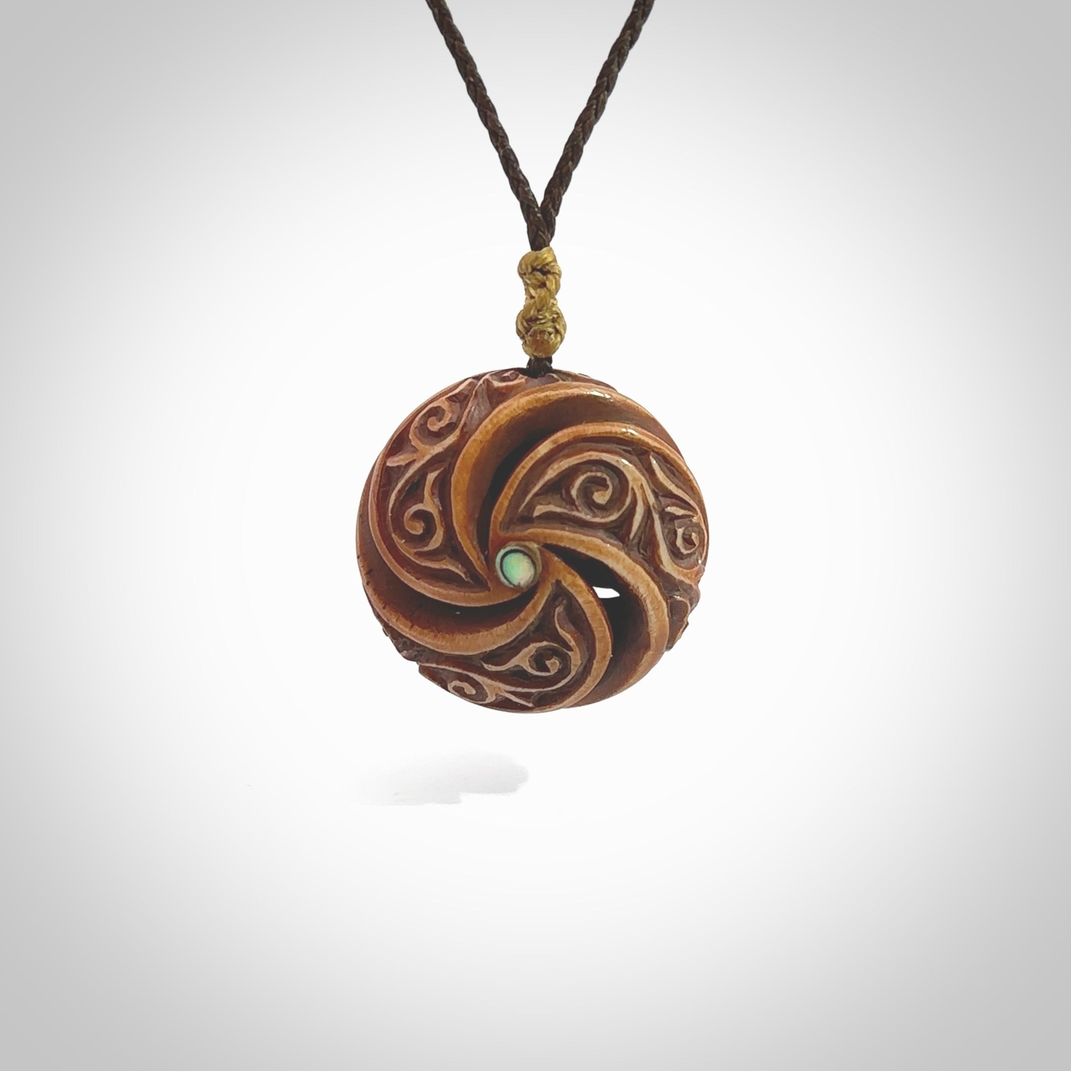 A hand carved and intricate koru pendant made for us by Yuri Terenyi. This is a beautiful little piece and is emblematic of the well known and loved Koru design. It is carved from bone in a hollowed, oval ball shape with decorative design carved into the koru. It is suspended from a chocolate brown cord which is adjustable.