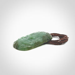 This picture shows a hand carved face pendant. It is a varied green colour which is quite beautiful. Although a medium piece, it is a wonderful, delicate piece of jewellery. The cord is hand plaited and adjustable so that you can position the pendant where it suits you best. Delivery is free worldwide.