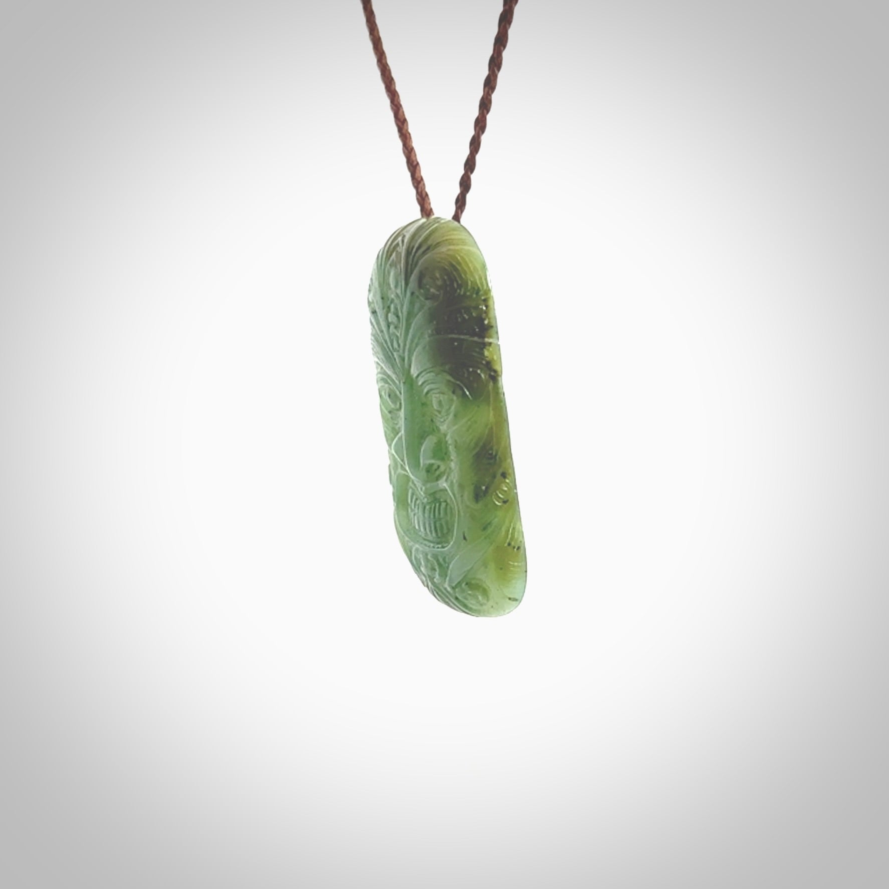 This picture shows a hand carved face pendant. It is a varied green colour which is quite beautiful. Although a medium piece, it is a wonderful, delicate piece of jewellery. The cord is hand plaited and adjustable so that you can position the pendant where it suits you best. Delivery is free worldwide.