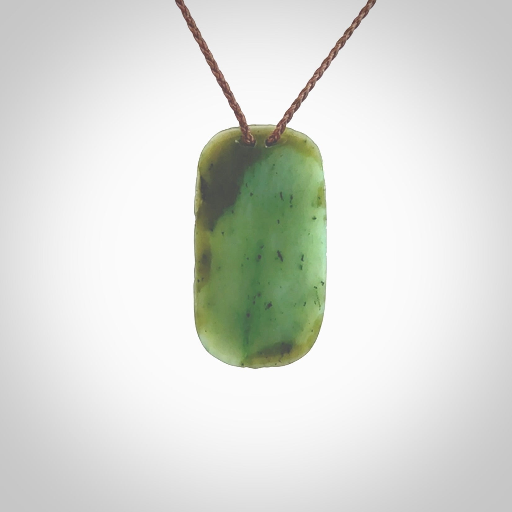 This picture shows a hand carved face pendant. It is a varied green colour which is quite beautiful. Although a medium piece, it is a wonderful, delicate piece of jewellery. The cord is hand plaited and adjustable so that you can position the pendant where it suits you best. Delivery is free worldwide.