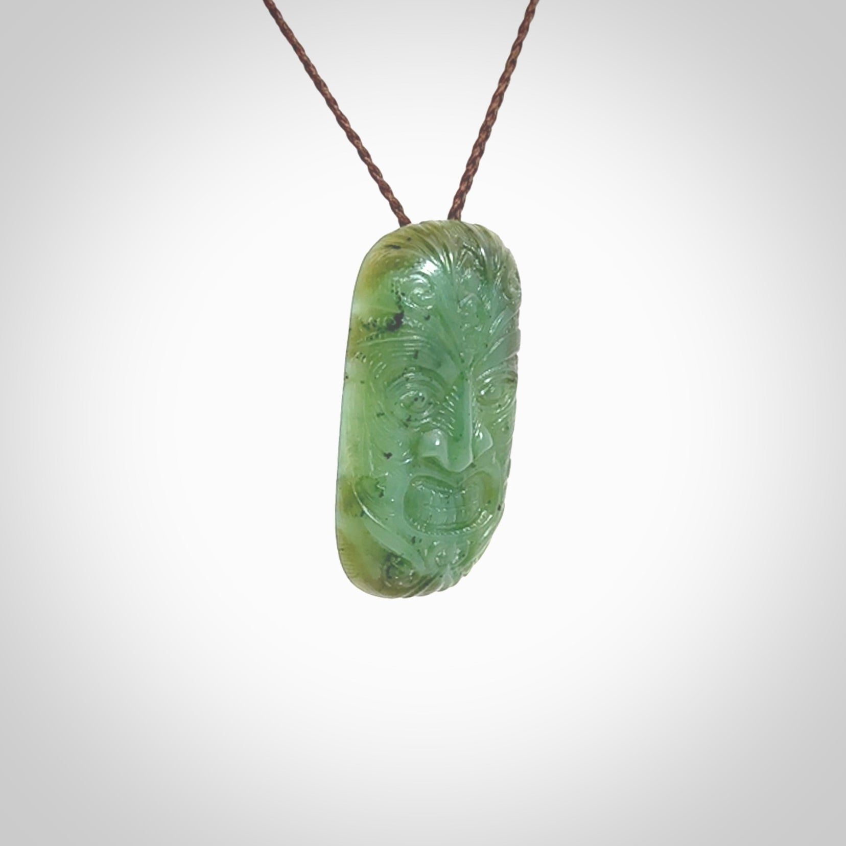 This picture shows a hand carved face pendant. It is a varied green colour which is quite beautiful. Although a medium piece, it is a wonderful, delicate piece of jewellery. The cord is hand plaited and adjustable so that you can position the pendant where it suits you best. Delivery is free worldwide.