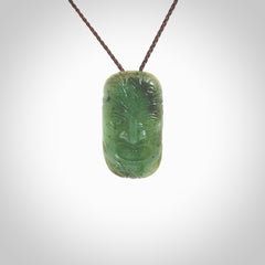 This picture shows a hand carved face pendant. It is a varied green colour which is quite beautiful. Although a medium piece, it is a wonderful, delicate piece of jewellery. The cord is hand plaited and adjustable so that you can position the pendant where it suits you best. Delivery is free worldwide.