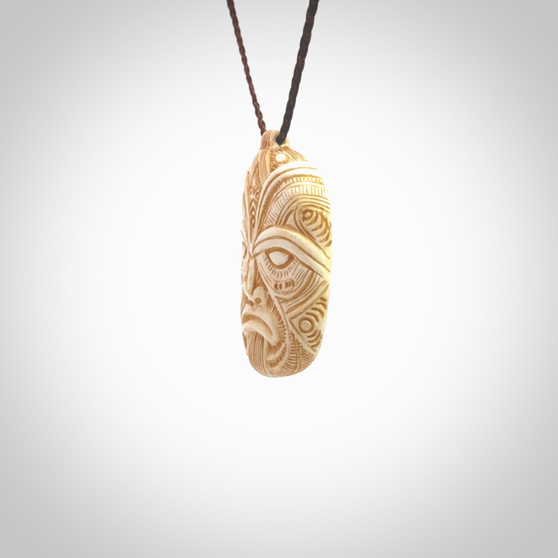 This picture shows a hand carved face pendant. It is carved from bone and although a medium piece, it is a wonderful, delicate piece of jewellery. The cord is hand plaited and adjustable so that you can position the pendant where it suits you best. Delivery is free worldwide.