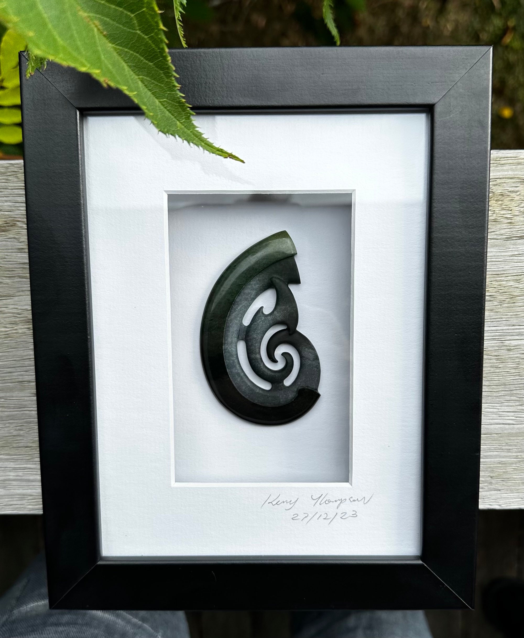 A hand carved large New Zealand Jade Hook, Matau, necklace that has been framed and signed by artist Kerry Thompson. A large sized hand made hook necklace by New Zealand artist Kerry Thompson. One off framed work of art to wear. Delivered with Express Courier.