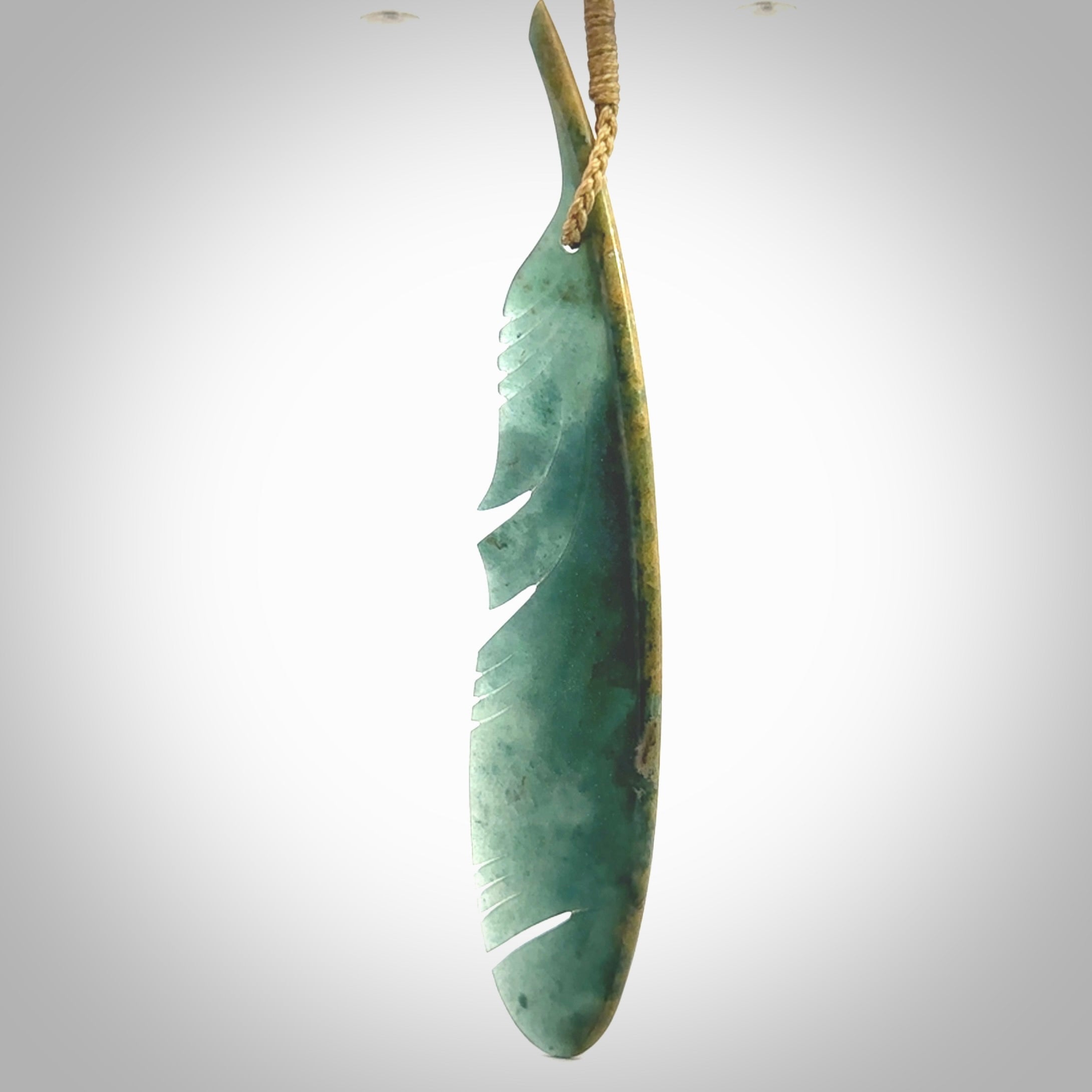 A hand carved large New Zealand Flower Jade Haast Eagle feather necklace. The cord is a tan colour and is a fixed length. A large sized hand made Jade Haast eagle feather pendant by New Zealand artist Kerry Thompson. One off work of art to wear.