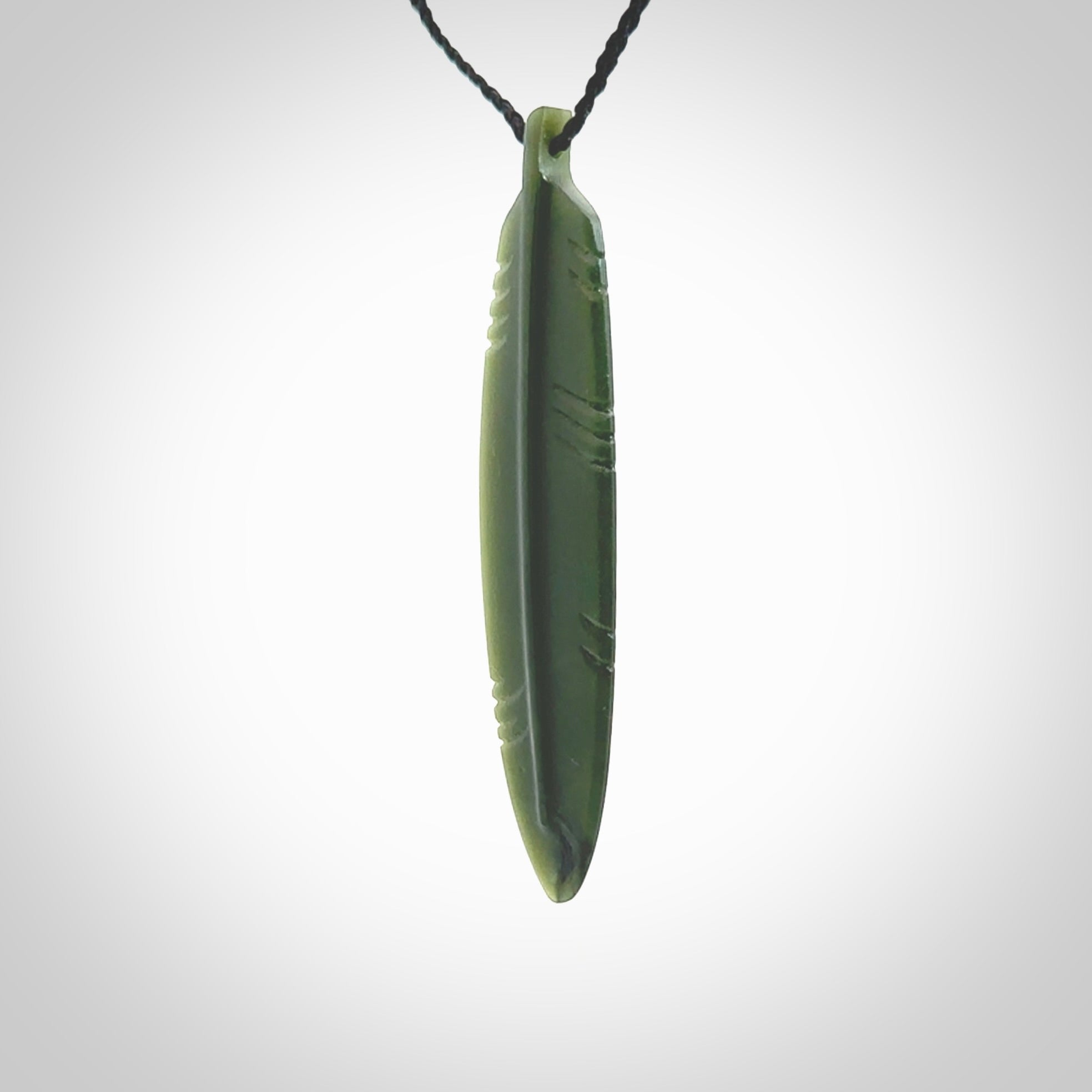 A hand carved large New Zealand Jade feather necklace. The cord is a black colour and is a fixed length. A large sized hand made Jade feather necklace by New Zealand artist Kerry Thompson. One off work of art to wear.