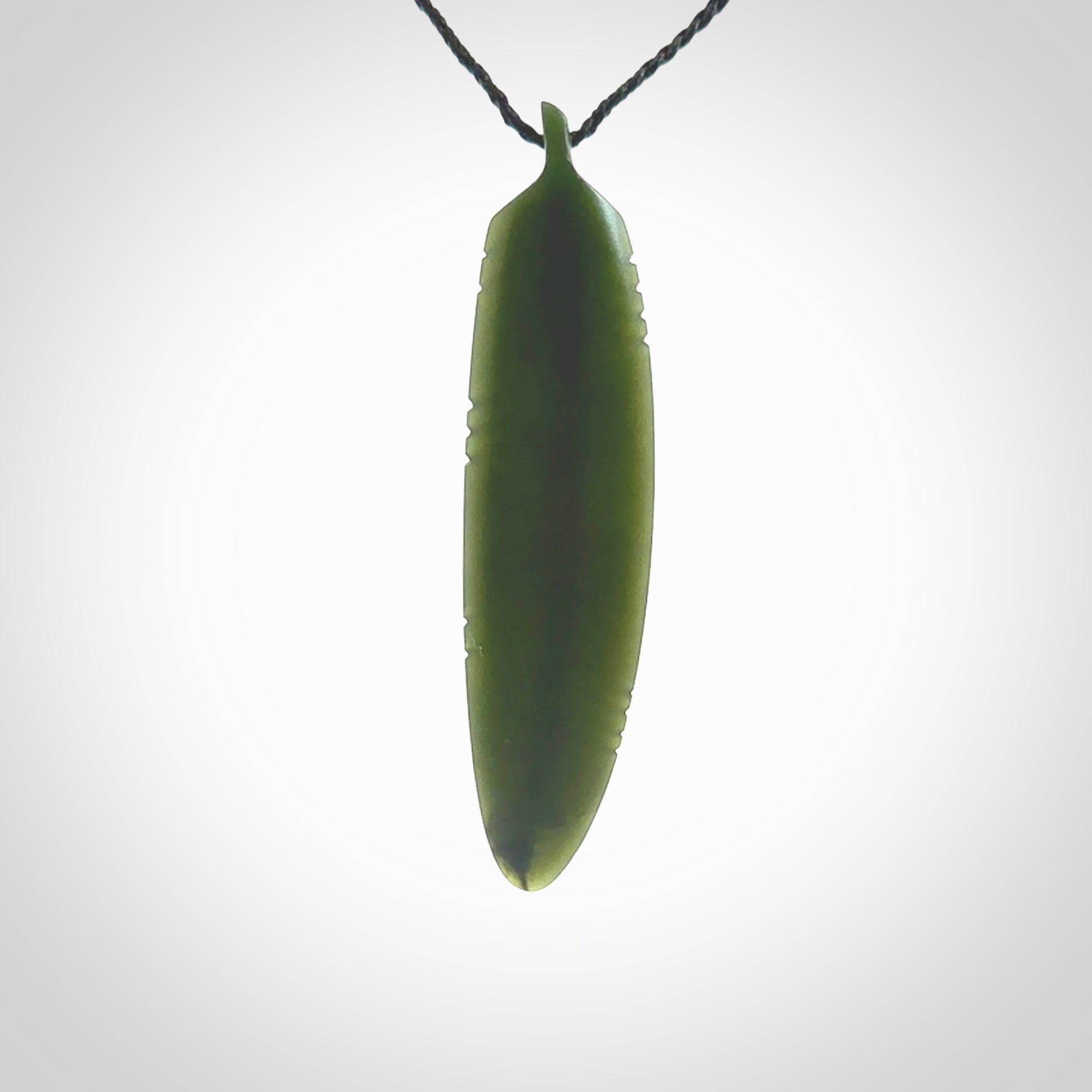 A hand carved large New Zealand Jade feather necklace. The cord is a black colour and is a fixed length. A large sized hand made Jade feather necklace by New Zealand artist Kerry Thompson. One off work of art to wear.