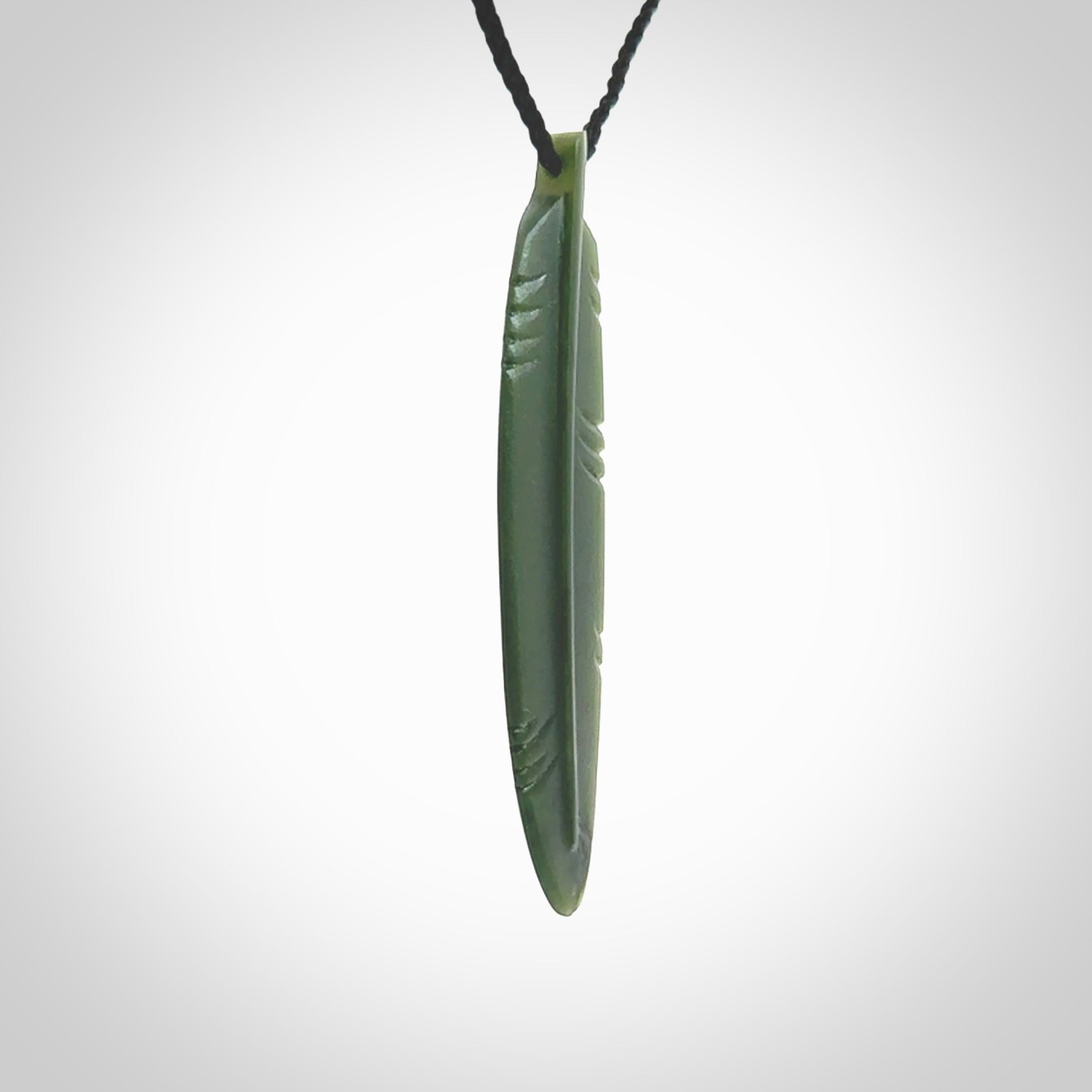 A hand carved large New Zealand Jade feather necklace. The cord is a black colour and is a fixed length. A large sized hand made Jade feather necklace by New Zealand artist Kerry Thompson. One off work of art to wear.