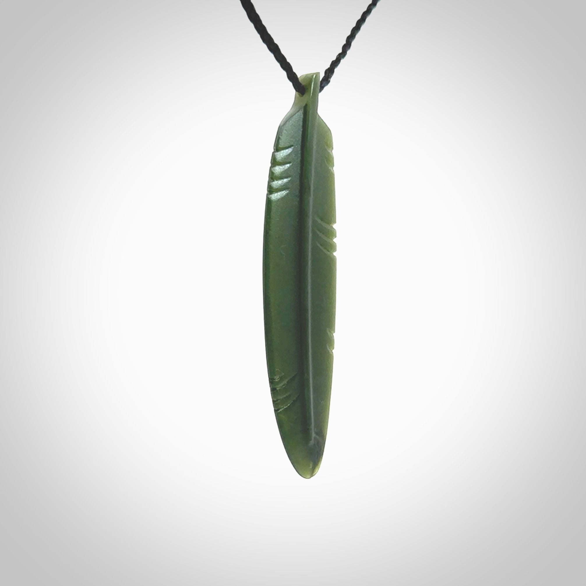 A hand carved large New Zealand Jade feather necklace. The cord is a black colour and is a fixed length. A large sized hand made Jade feather necklace by New Zealand artist Kerry Thompson. One off work of art to wear.