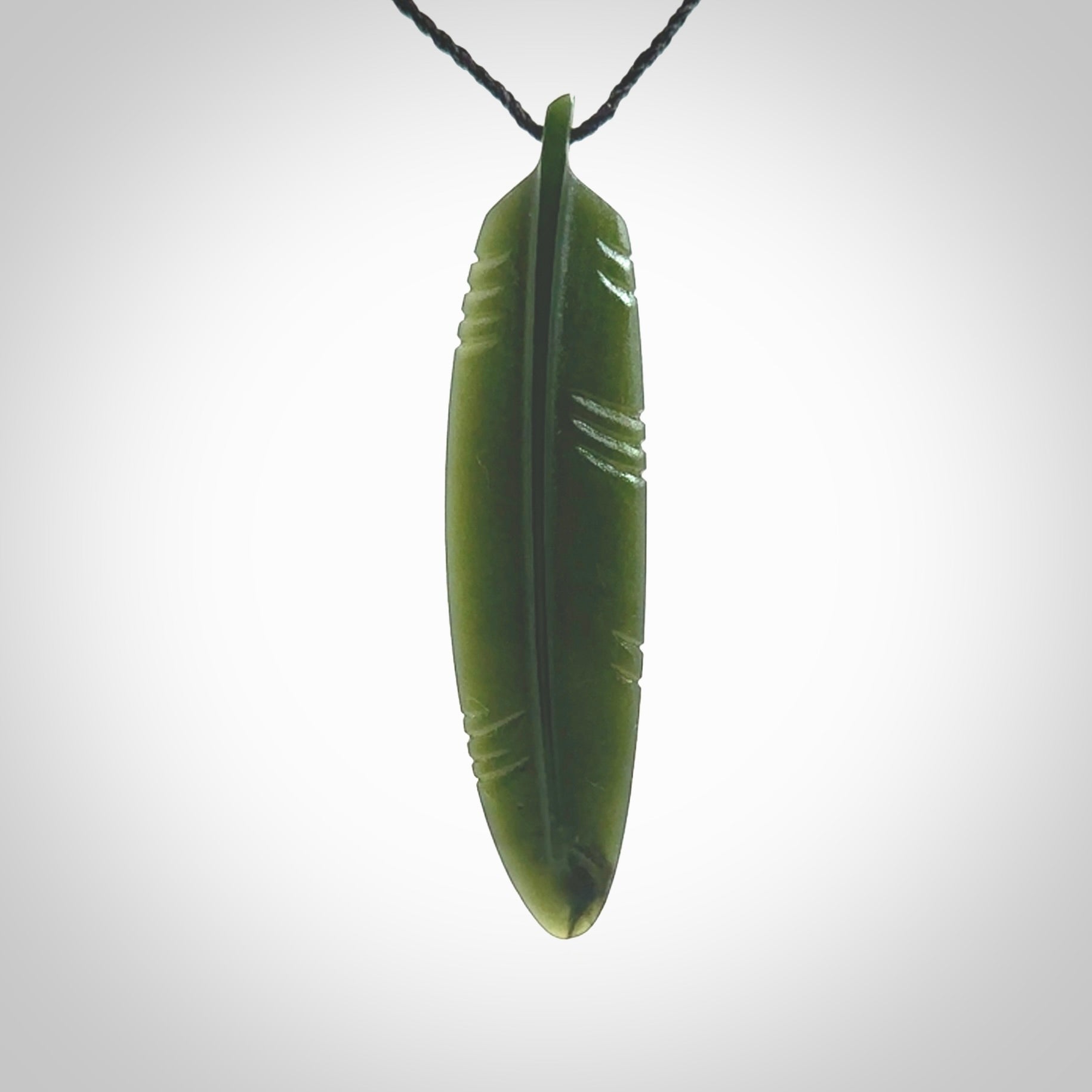 A hand carved large New Zealand Jade feather necklace. The cord is a black colour and is a fixed length. A large sized hand made Jade feather necklace by New Zealand artist Kerry Thompson. One off work of art to wear.