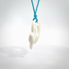 A hand carved bone whale pendant. This is a lovely piece carved to bring pleasure to the lucky wearer. It is a friendly pendant which we will ship to you free wherever you live. Carved by NZ Pacific and for sale online. Provided with an adjustable paradise blue cord.