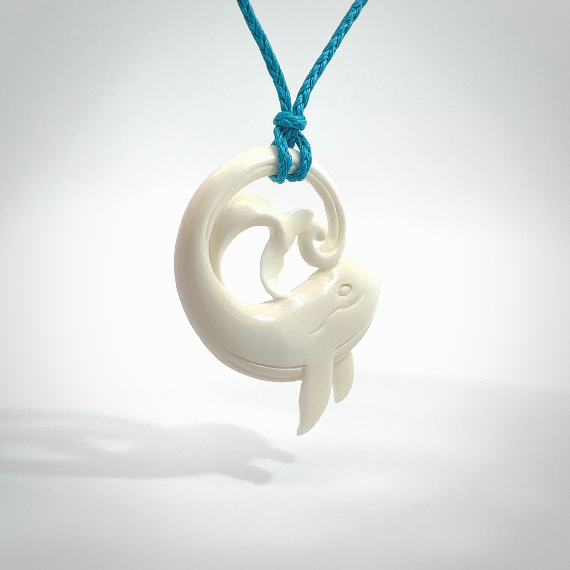 A hand carved bone whale pendant. This is a lovely piece carved to bring pleasure to the lucky wearer. It is a friendly pendant which we will ship to you free wherever you live. Carved by NZ Pacific and for sale online. Provided with an adjustable paradise blue cord.