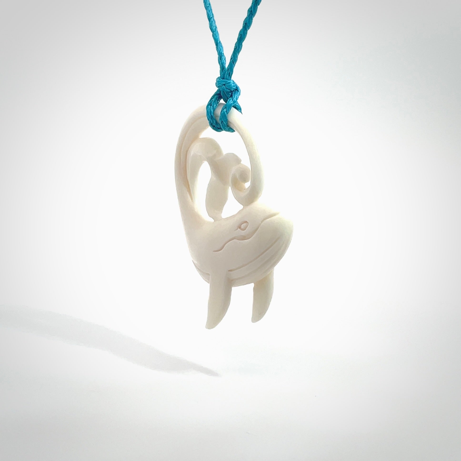 A hand carved bone whale pendant. This is a lovely piece carved to bring pleasure to the lucky wearer. It is a friendly pendant which we will ship to you free wherever you live. Carved by NZ Pacific and for sale online. Provided with an adjustable paradise blue cord.