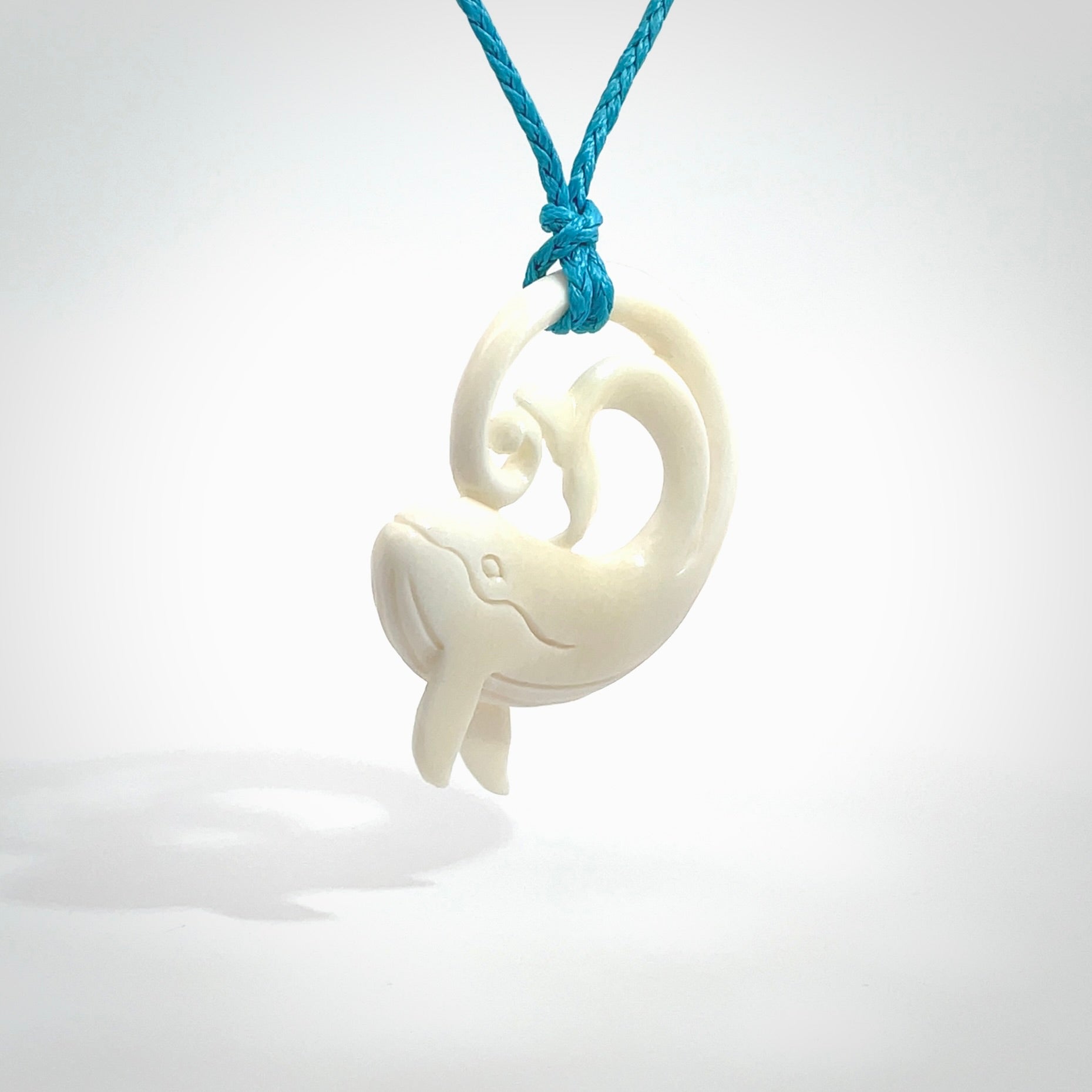 A hand carved bone whale pendant. This is a lovely piece carved to bring pleasure to the lucky wearer. It is a friendly pendant which we will ship to you free wherever you live. Carved by NZ Pacific and for sale online. Provided with an adjustable paradise blue cord.