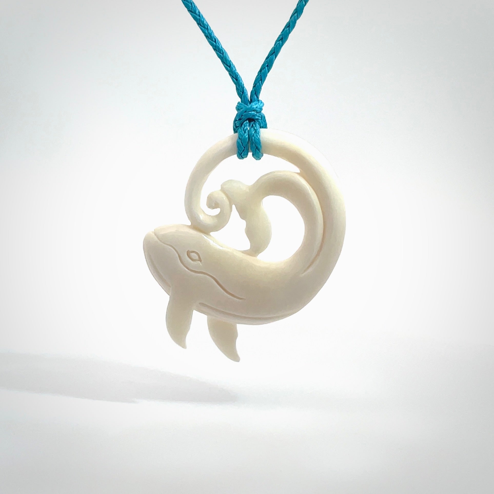 A hand carved bone whale pendant. This is a lovely piece carved to bring pleasure to the lucky wearer. It is a friendly pendant which we will ship to you free wherever you live. Carved by NZ Pacific and for sale online. Provided with an adjustable paradise blue cord.