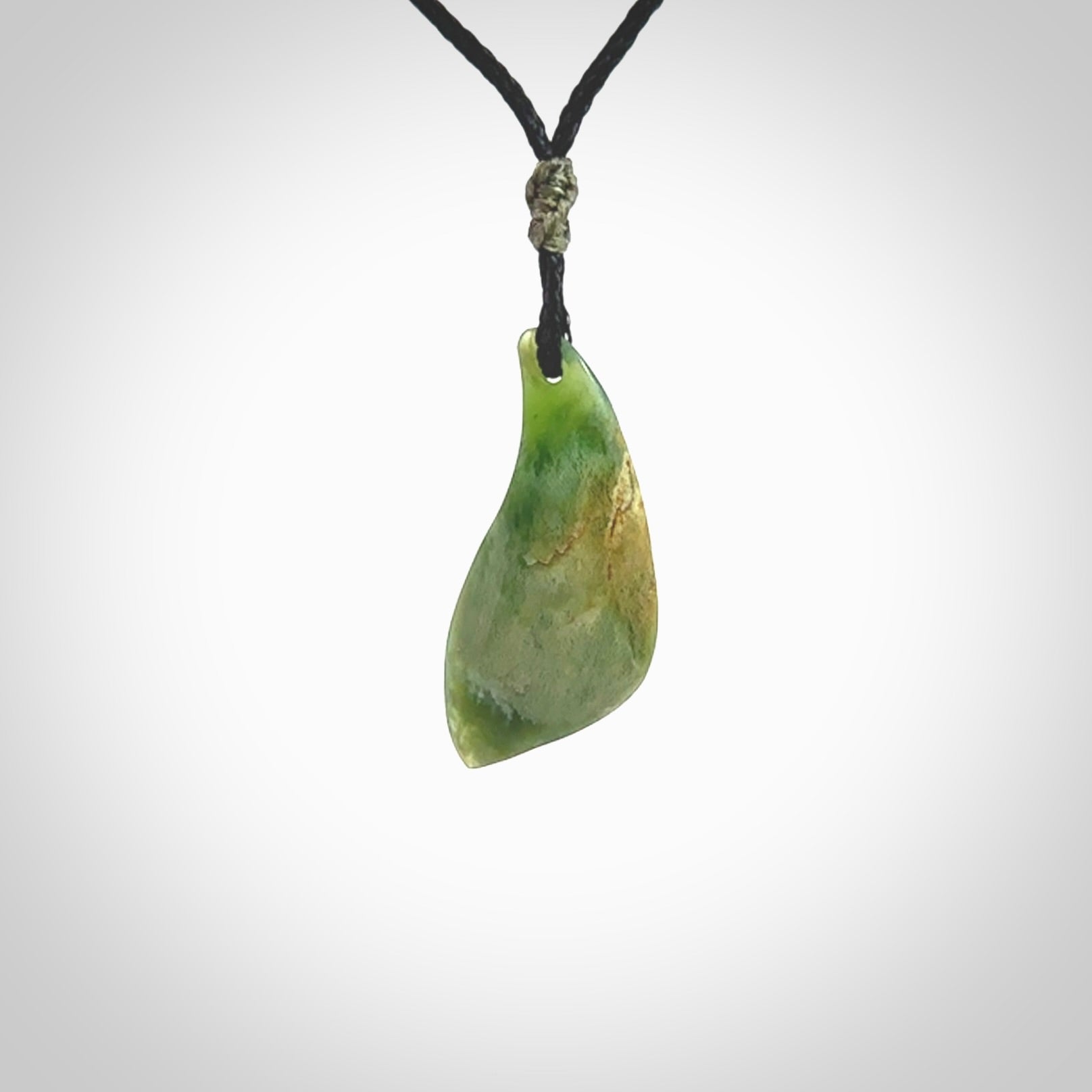 A lovely small sized New Zealand Marsden jade drop pendant. This piece is made from a deep green jade with orange specks and is a wonderful colour. Carved for NZ Pacific and delivered worldwide. Provided with an adjustable black cord.