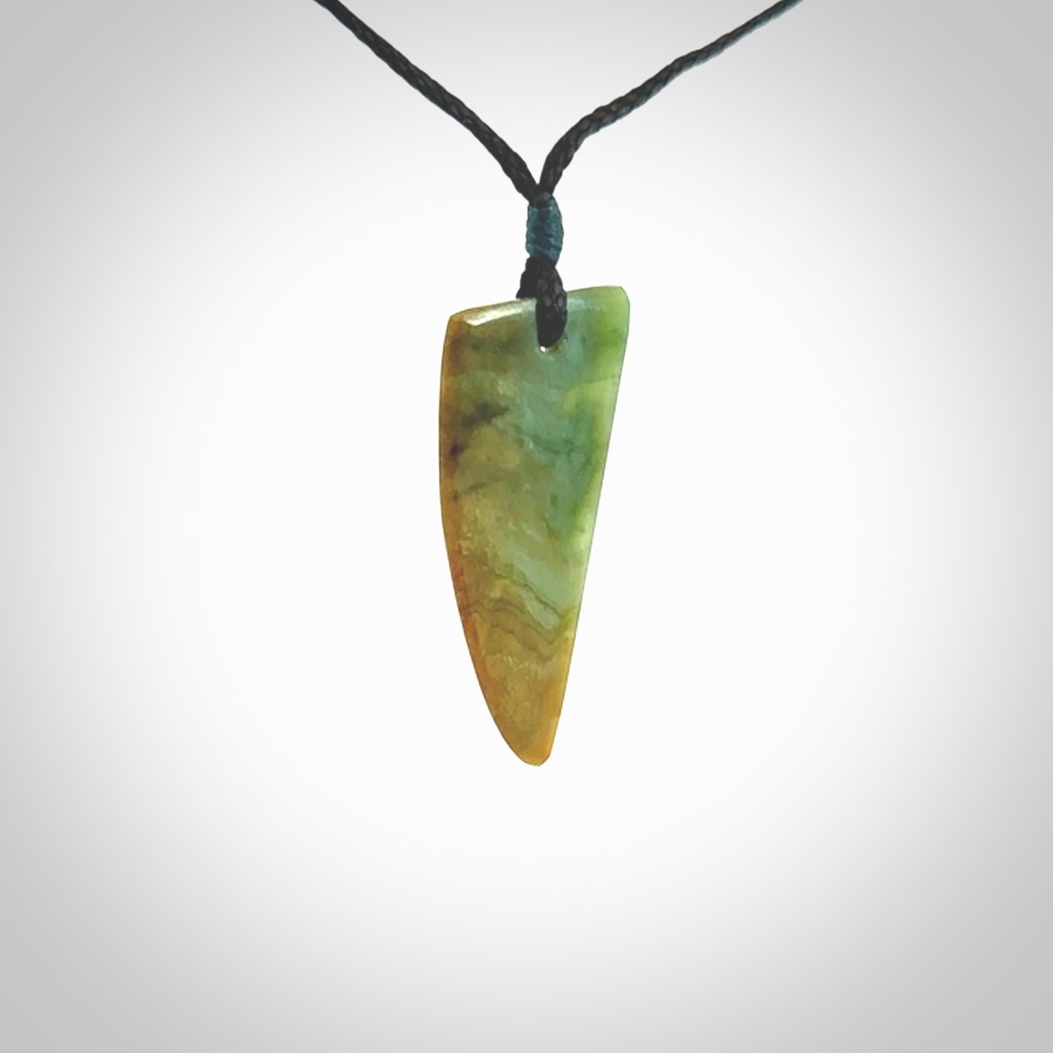 This photo shows a medium jade drop shaped pendant. It a a lovely varied green and orange New Zealand Marsden jade. The cord is black and is adjustable in length. One only medium, contemporary drop necklace from Jade.