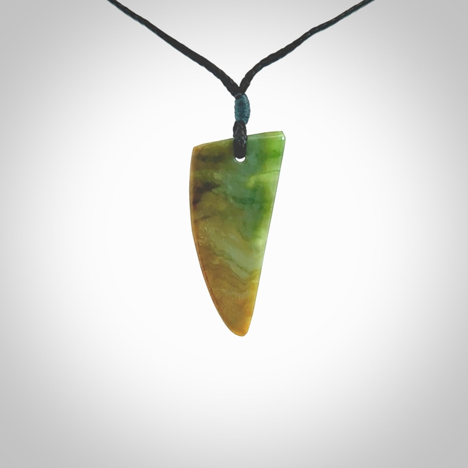 This photo shows a medium jade drop shaped pendant. It a a lovely varied green and orange New Zealand Marsden jade. The cord is black and is adjustable in length. One only medium, contemporary drop necklace from Jade.