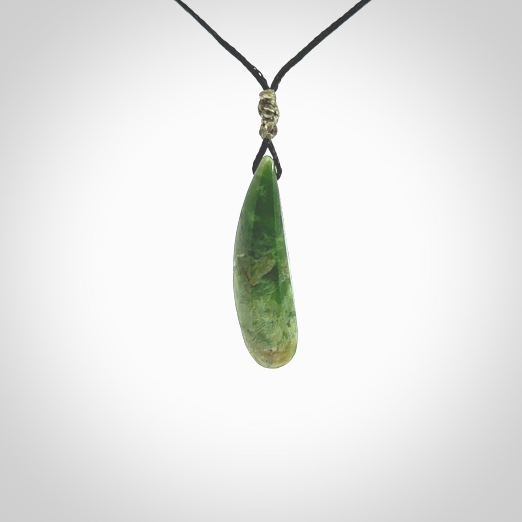 A lovely small sized New Zealand Marsden jade drop pendant. This piece is made from a deep green jade with orange specks and is a wonderful colour. Carved for NZ Pacific and delivered worldwide. Provided with an adjustable black cord.