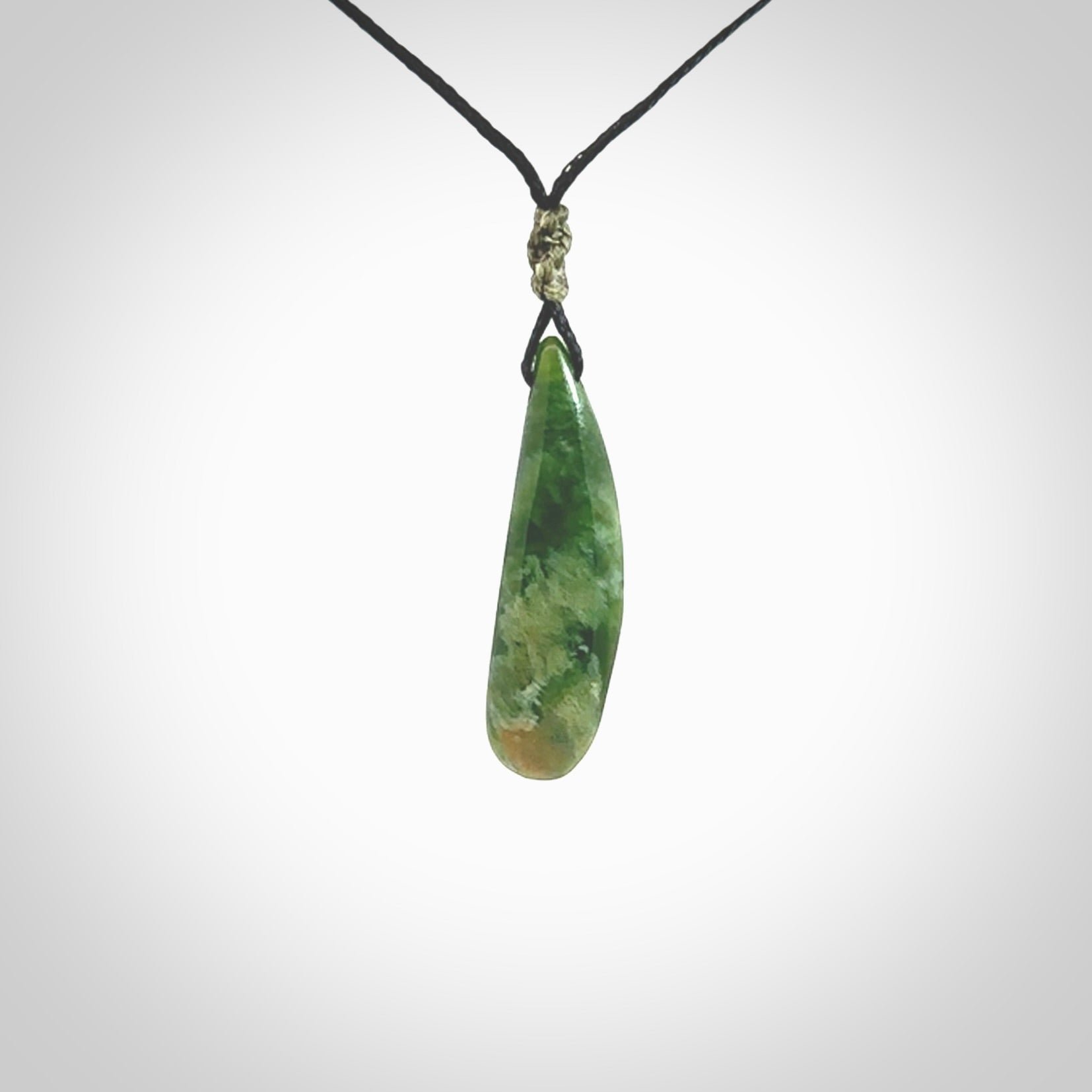 A lovely small sized New Zealand Marsden jade drop pendant. This piece is made from a deep green jade with orange specks and is a wonderful colour. Carved for NZ Pacific and delivered worldwide. Provided with an adjustable black cord.