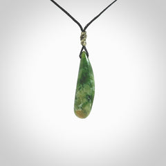 A lovely small sized New Zealand Marsden jade drop pendant. This piece is made from a deep green jade with orange specks and is a wonderful colour. Carved for NZ Pacific and delivered worldwide. Provided with an adjustable black cord.