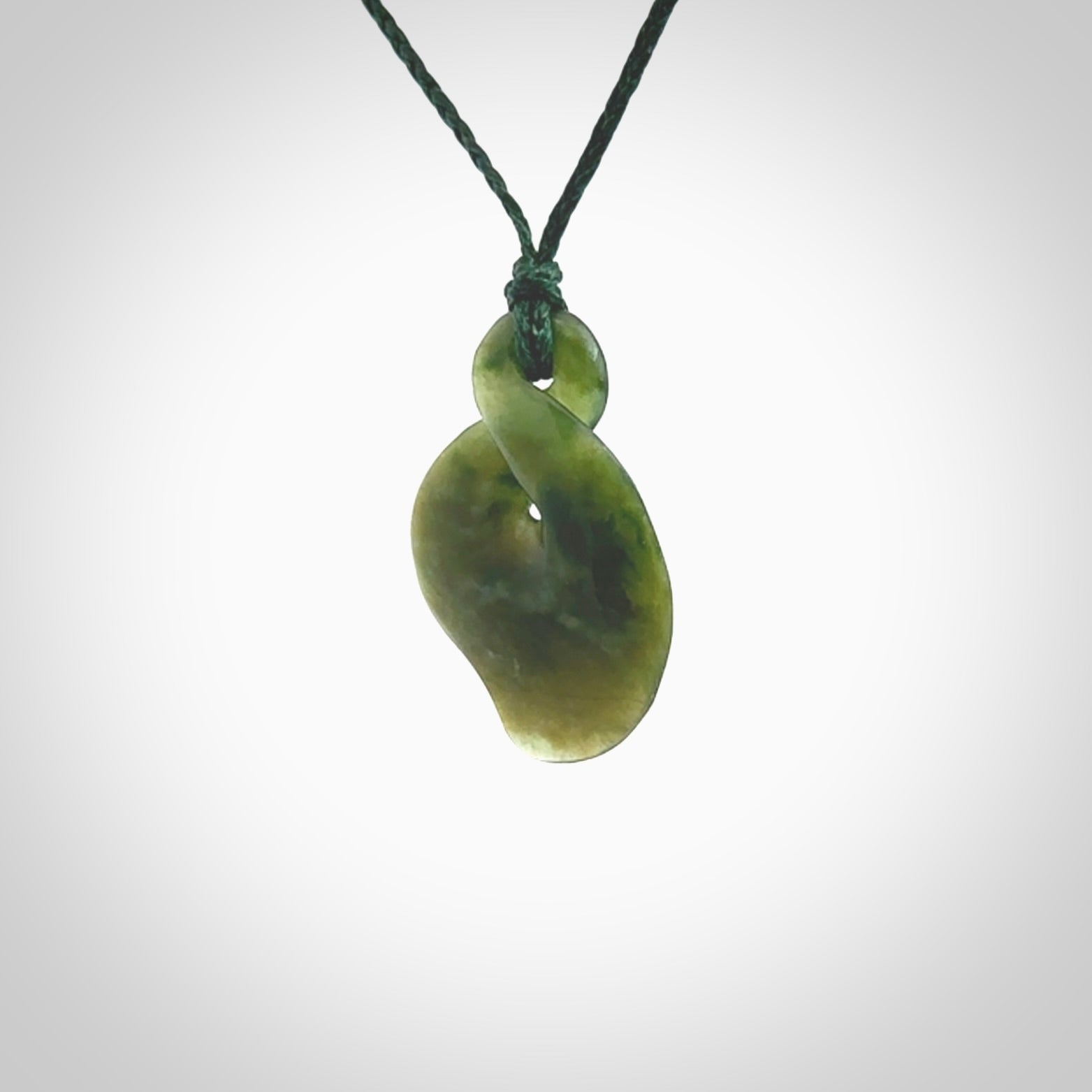 This piece is a fine, delicate drop shaped, single twist pendant. It was carved for us from a lovely semi-translucent green piece of New Zealand jade. It is suspended on an green braided cord that is length adjustable.