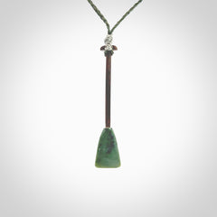 This little pendant is a hand carved dragon boat paddle. We have carved this with a Green Nephrite jade blade and a hardwood handle. It is a necklace that was carved for suffered of breast cancer who are members of the Pink Dragons, a group or cancer fighters who take part in Dragon Boat racing events around the world.