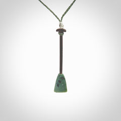 This little pendant is a hand carved dragon boat paddle. We have carved this with a Green Nephrite jade blade and a hardwood handle. It is a necklace that was carved for suffered of breast cancer who are members of the Pink Dragons, a group or cancer fighters who take part in Dragon Boat racing events around the world.