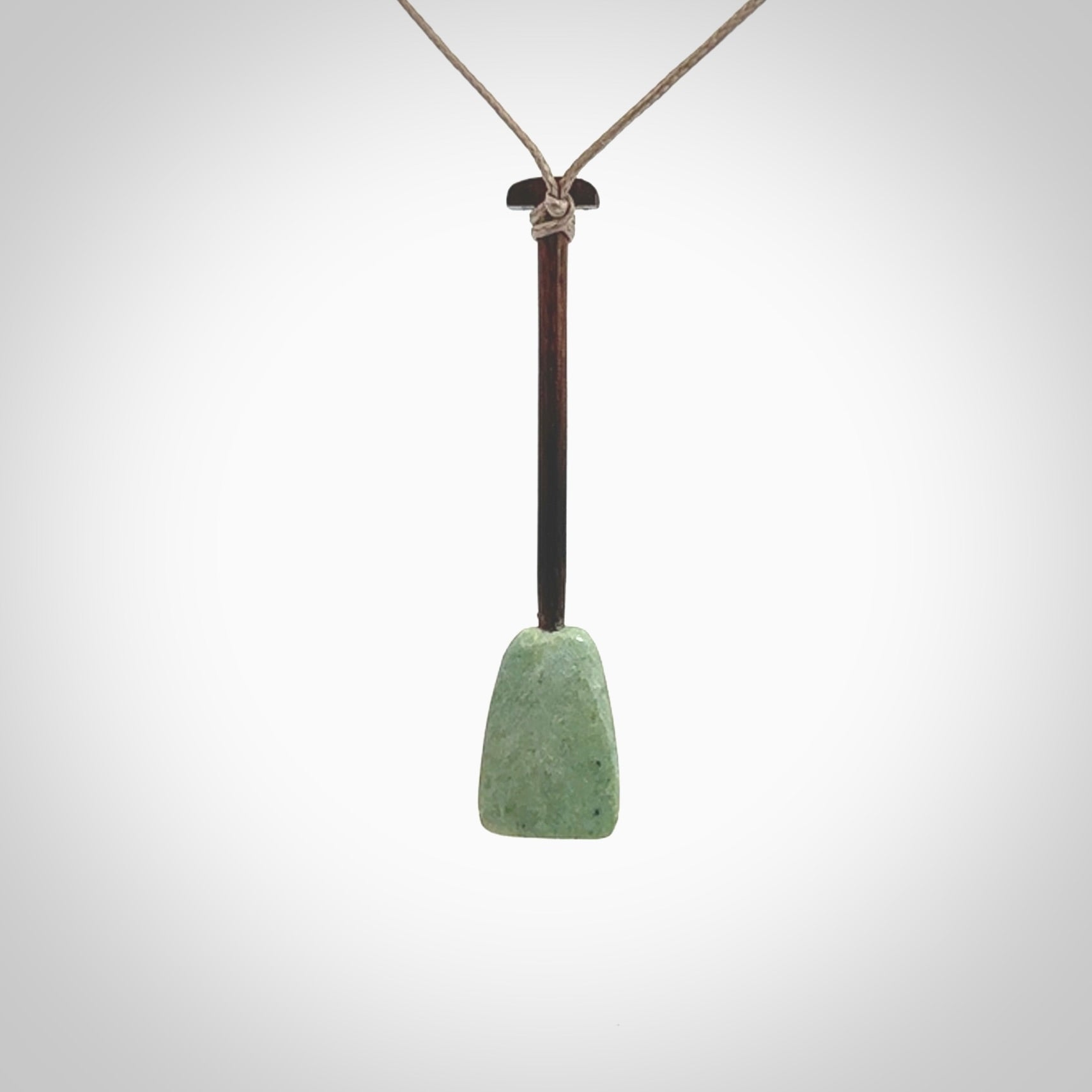 This little pendant is a hand carved dragon boat paddle. We have carved this with a Green Nephrite jade blade and a hardwood handle. It is a necklace that was carved for suffered of breast cancer who are members of the Pink Dragons, a group or cancer fighters who take part in Dragon Boat racing events around the world.