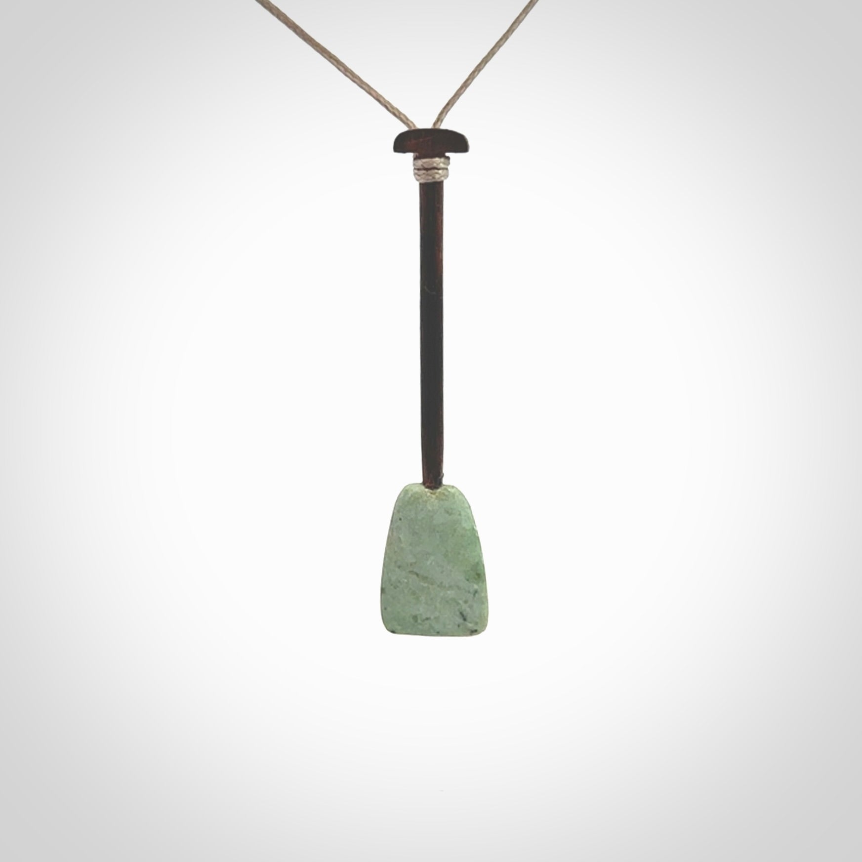 This little pendant is a hand carved dragon boat paddle. We have carved this with a Green Nephrite jade blade and a hardwood handle. It is a necklace that was carved for suffered of breast cancer who are members of the Pink Dragons, a group or cancer fighters who take part in Dragon Boat racing events around the world.