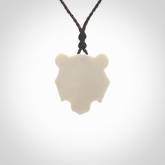 This picture shows a grizzly bear pendant that we designed in bone with buffalo horn inlay eyes. It is a grizzly bear head that is carved in detail. A really attractive and eye-catching piece of handmade jewellery. The cord is hand plaited braid in brown and the length can be adjusted.