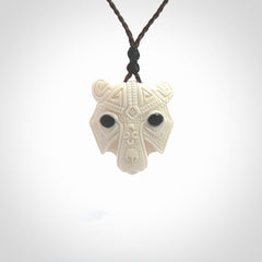 This picture shows a grizzly bear pendant that we designed in bone with buffalo horn inlay eyes. It is a grizzly bear head that is carved in detail. A really attractive and eye-catching piece of handmade jewellery. The cord is hand plaited braid in brown and the length can be adjusted.