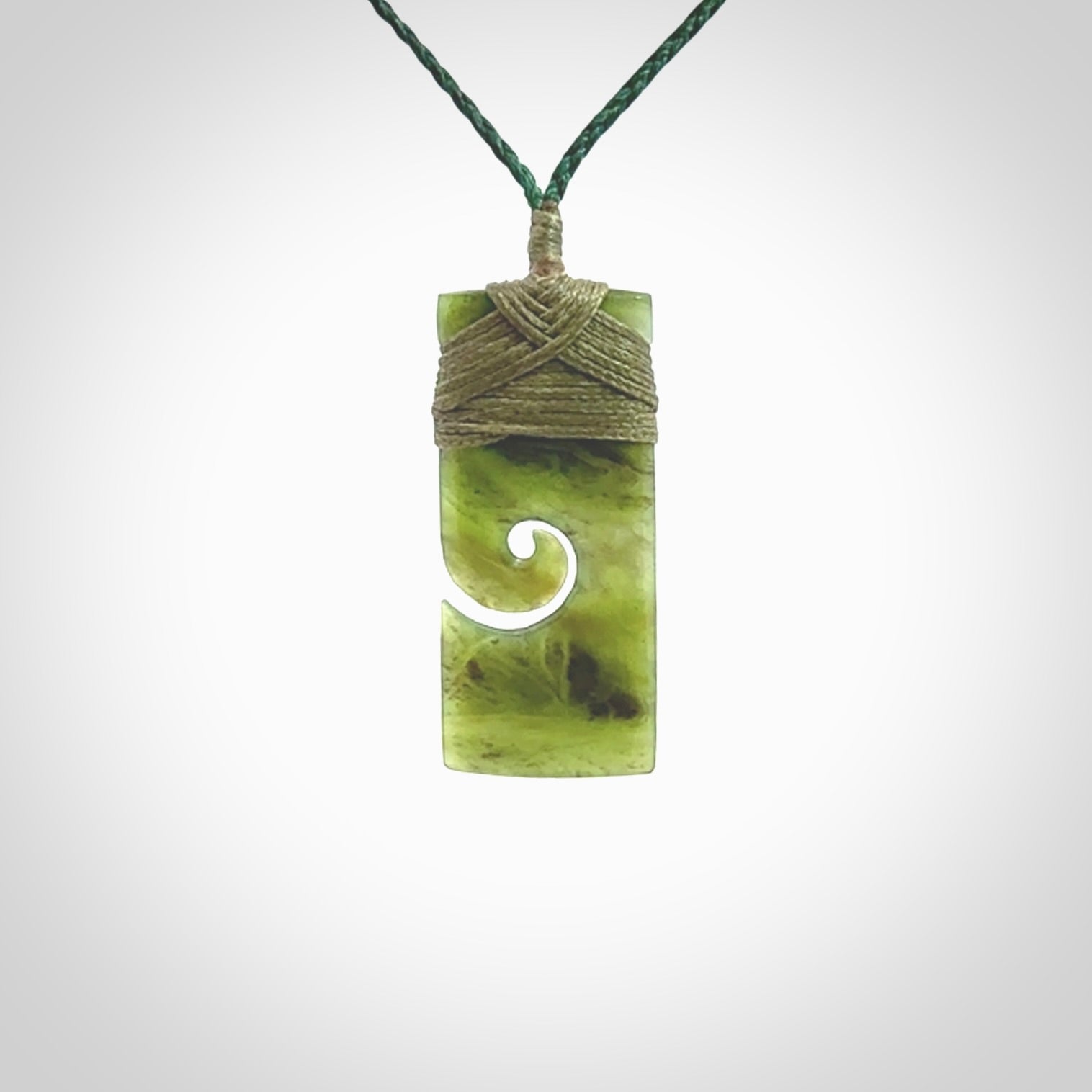 This picture shows a small toki pendant with a koru carved into the side. The cord is plaited and is length adjustable. This is a small toki pendant carved from beautiful New Zealand jade.