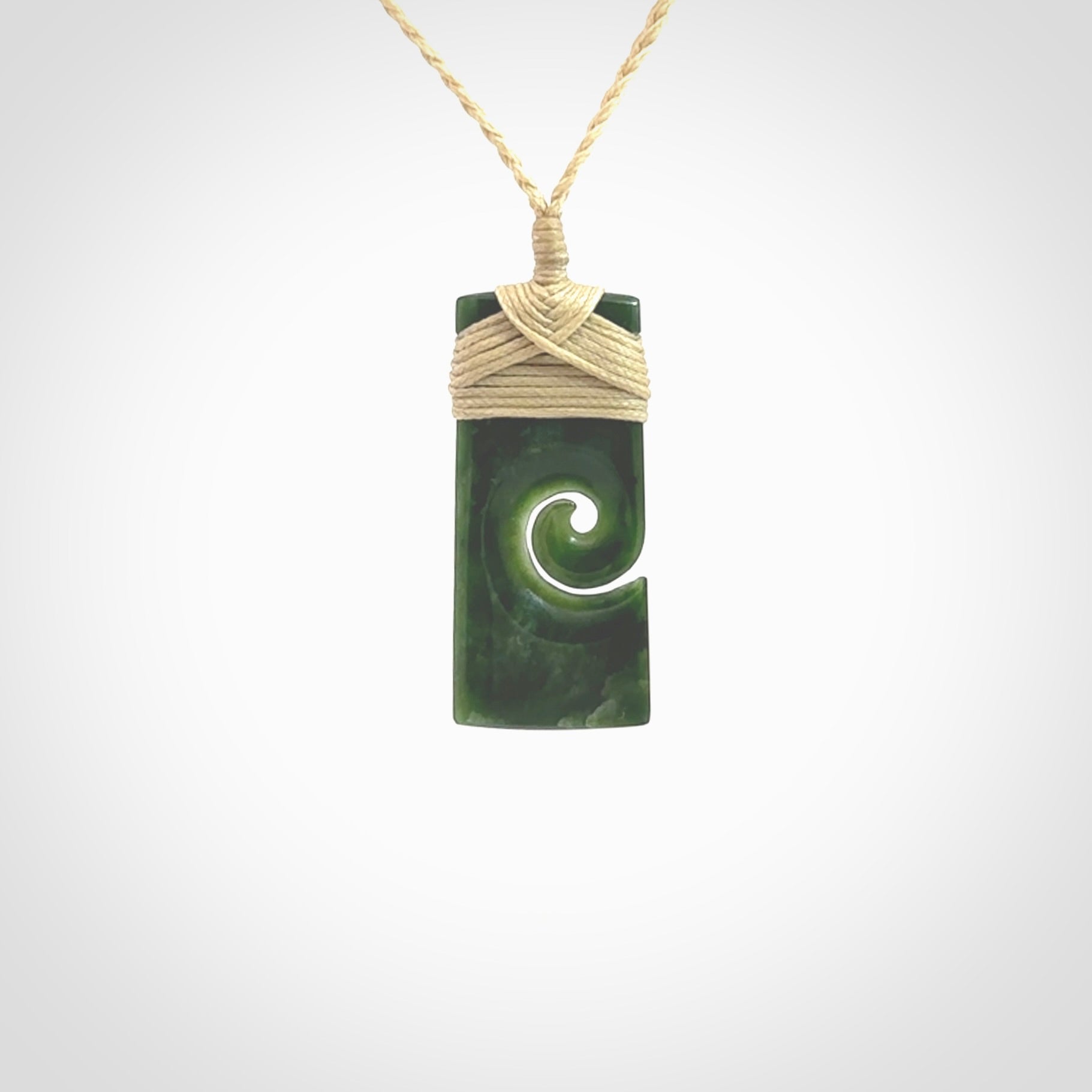 This picture shows a small toki pendant with a koru carved into the side. The cord is plaited and is length adjustable. This is a small toki pendant carved from beautiful New Zealand jade.