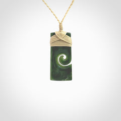 This picture shows a small toki pendant with a koru carved into the side. The cord is plaited and is length adjustable. This is a small toki pendant carved from beautiful New Zealand jade.