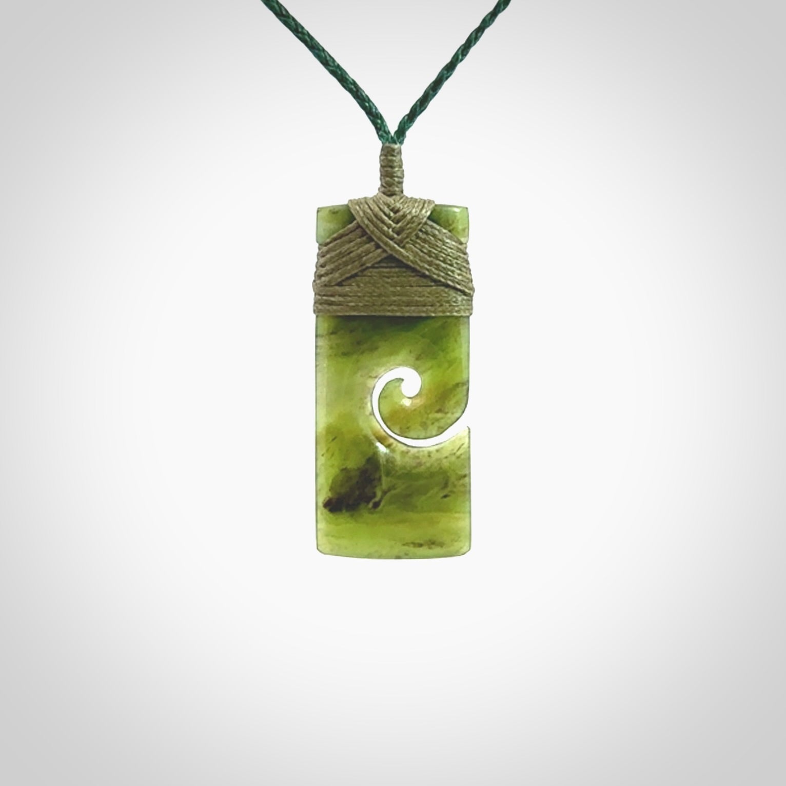 This picture shows a small toki pendant with a koru carved into the side. The cord is plaited and is length adjustable. This is a small toki pendant carved from beautiful New Zealand jade.