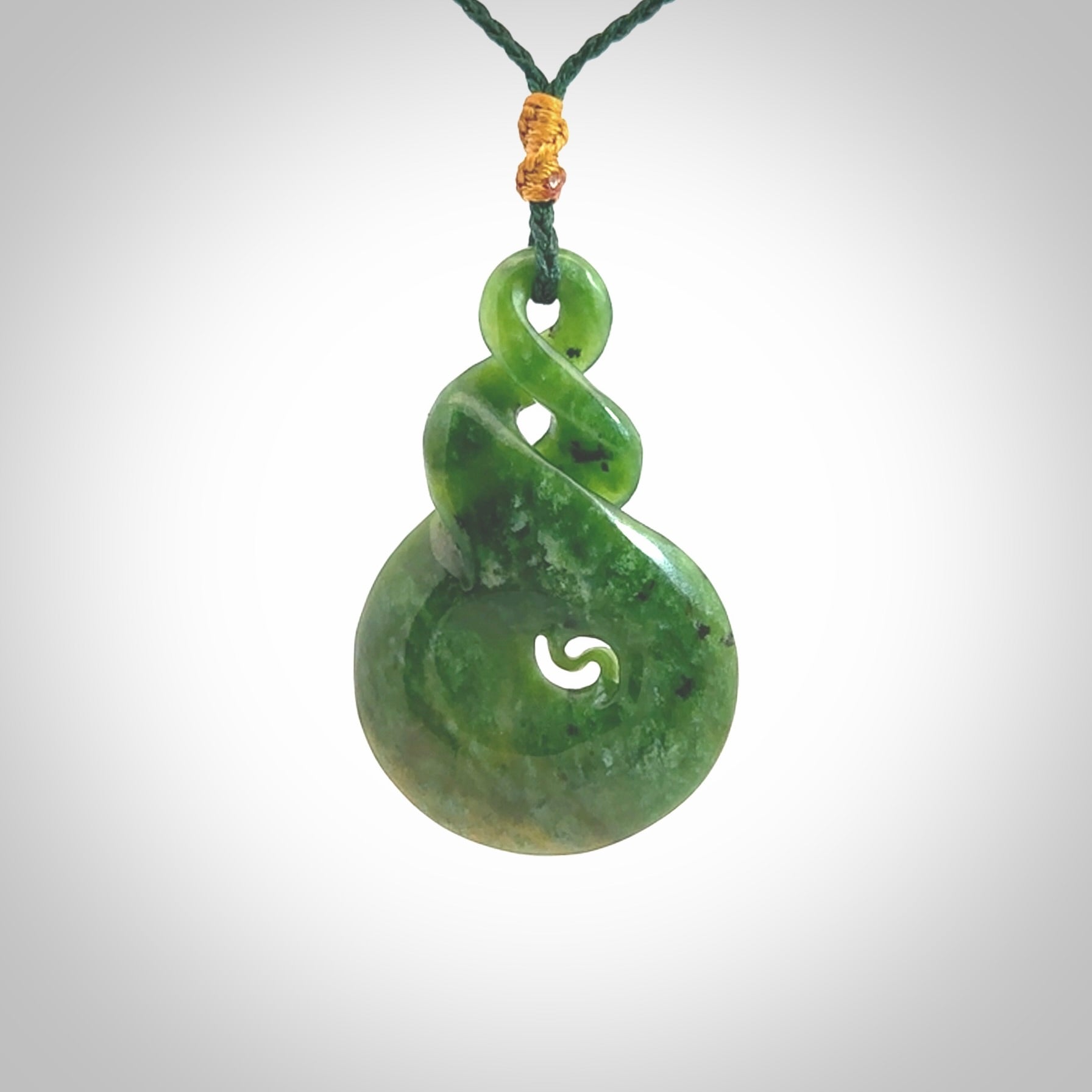 Ross Crump double twist with koru pendant. Hand carved from rare New Zealand Flower jade this is a beautiful pounamu pendant. The cord is length adjustable. It is a delicate and very beautiful greenstone pendant. For sale online by NZ Pacific.