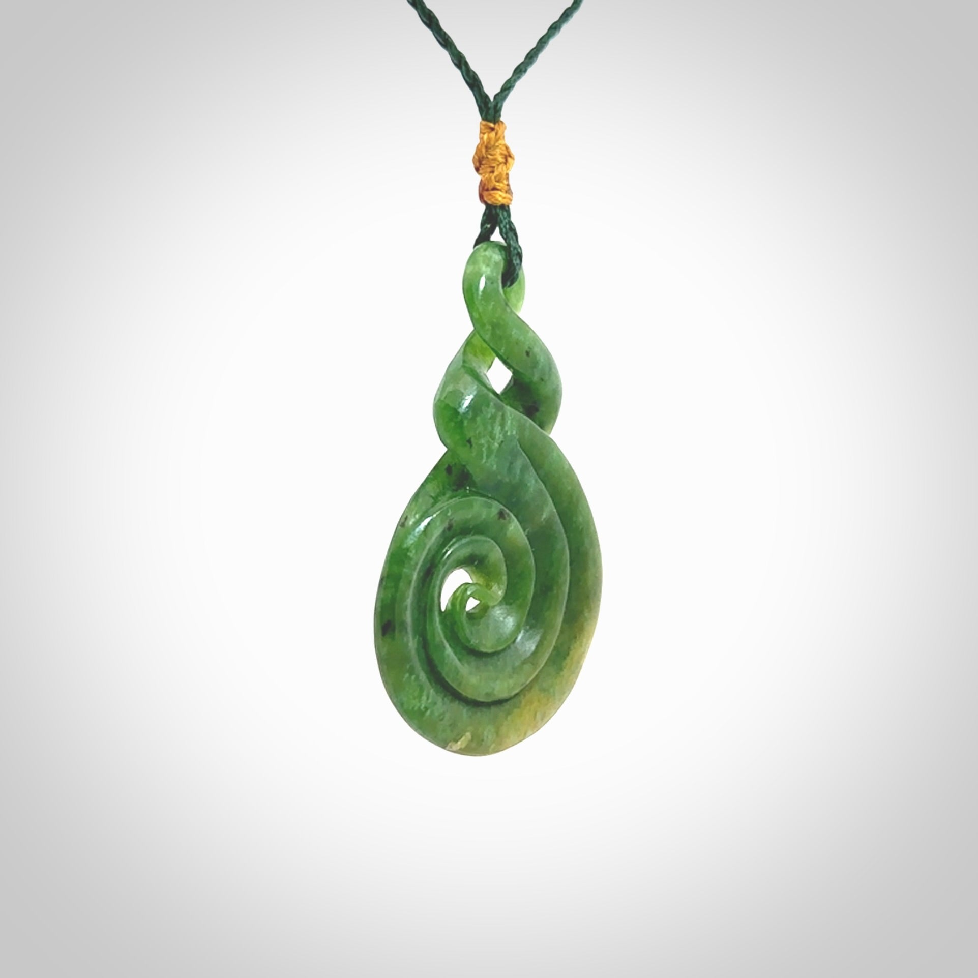 Ross Crump double twist with koru pendant. Hand carved from rare New Zealand Flower jade this is a beautiful pounamu pendant. The cord is length adjustable. It is a delicate and very beautiful greenstone pendant. For sale online by NZ Pacific.