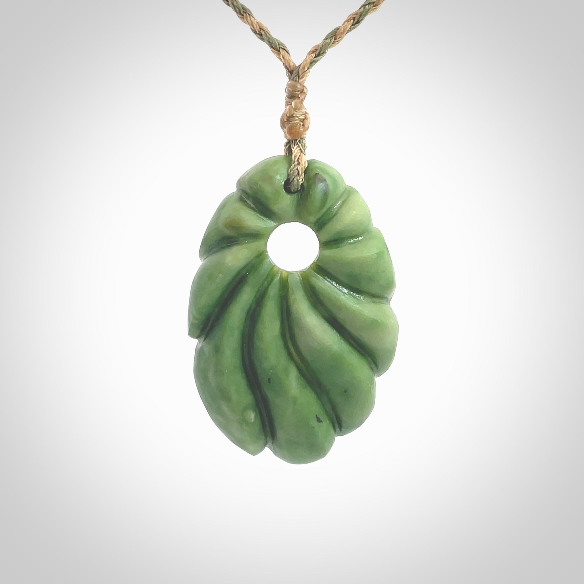 This picture shows a contemporary drop shaped pendant, hand carved from New Zealand flower jade. We will provide this with an adjustable plaited cord. Hand crafted stunning New Zealand Marsden Flower Jade drop pendant by Ana Krakosky.