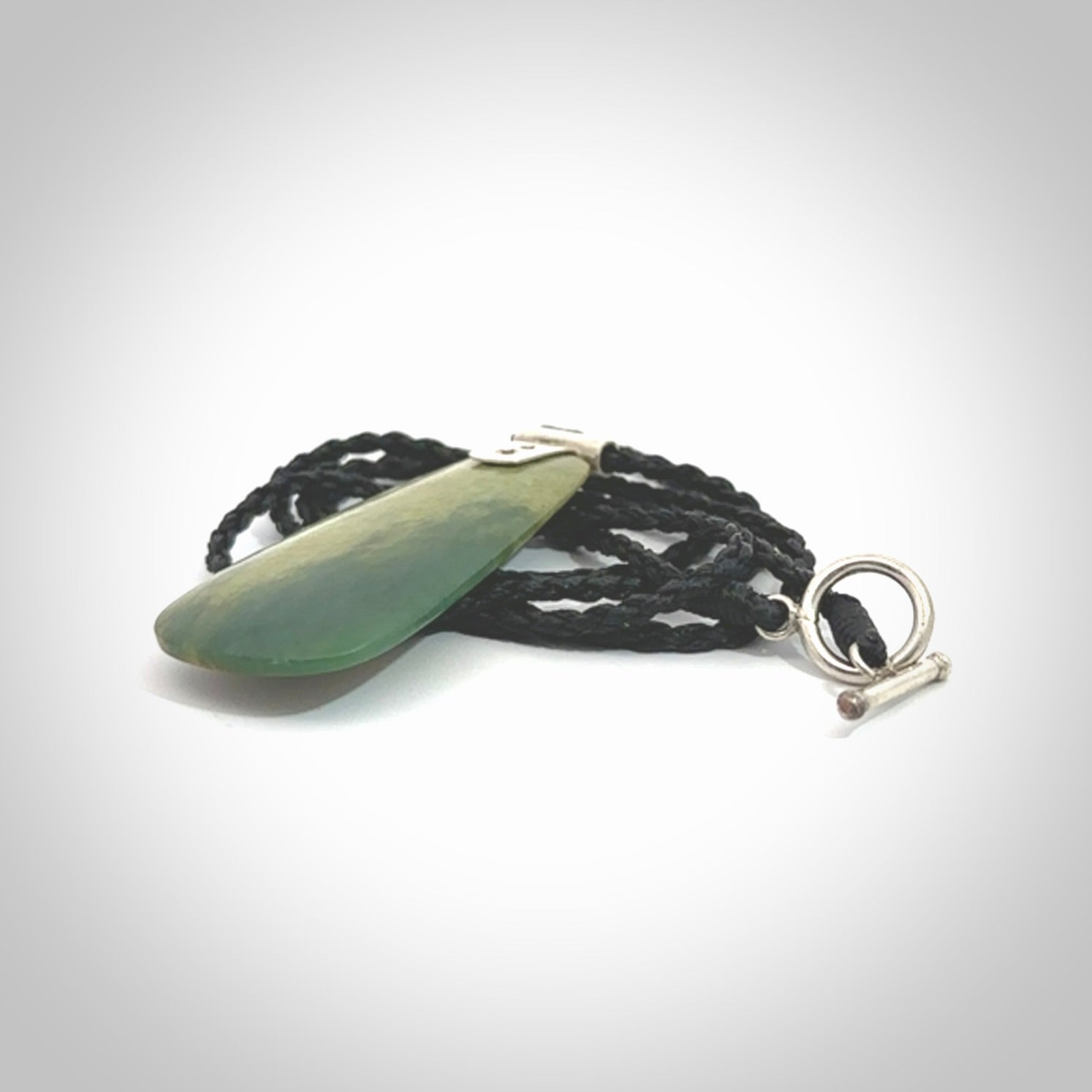 This photo shows a drop pendant suspended from a black cord. The jade is a lovely light flower jade with sterling silver. A lovely soft New Zealand flower jade pendant carved for us by Josey Coyle.