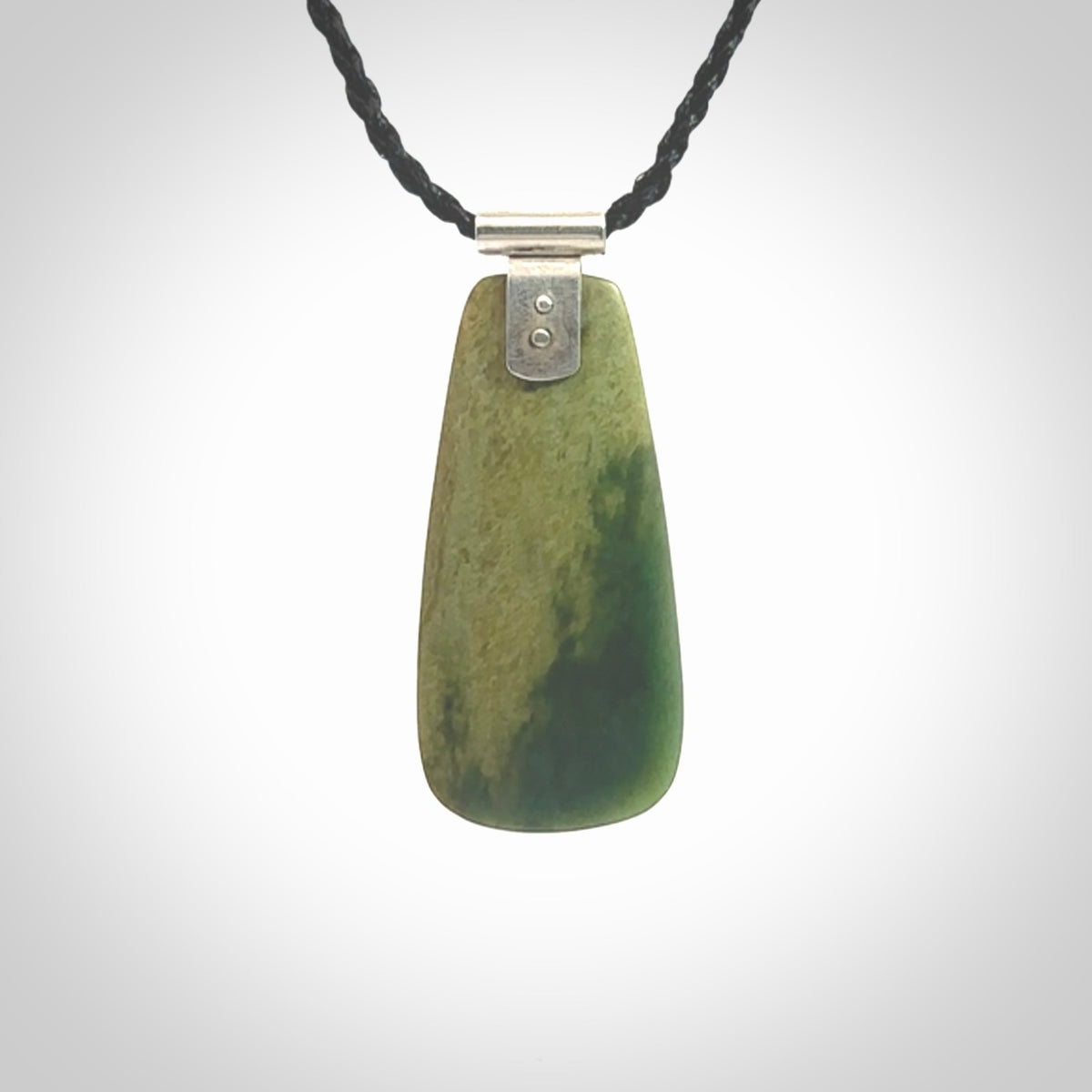 This photo shows a drop pendant suspended from a black cord. The jade is a lovely light flower jade with sterling silver. A lovely soft New Zealand flower jade pendant carved for us by Josey Coyle.