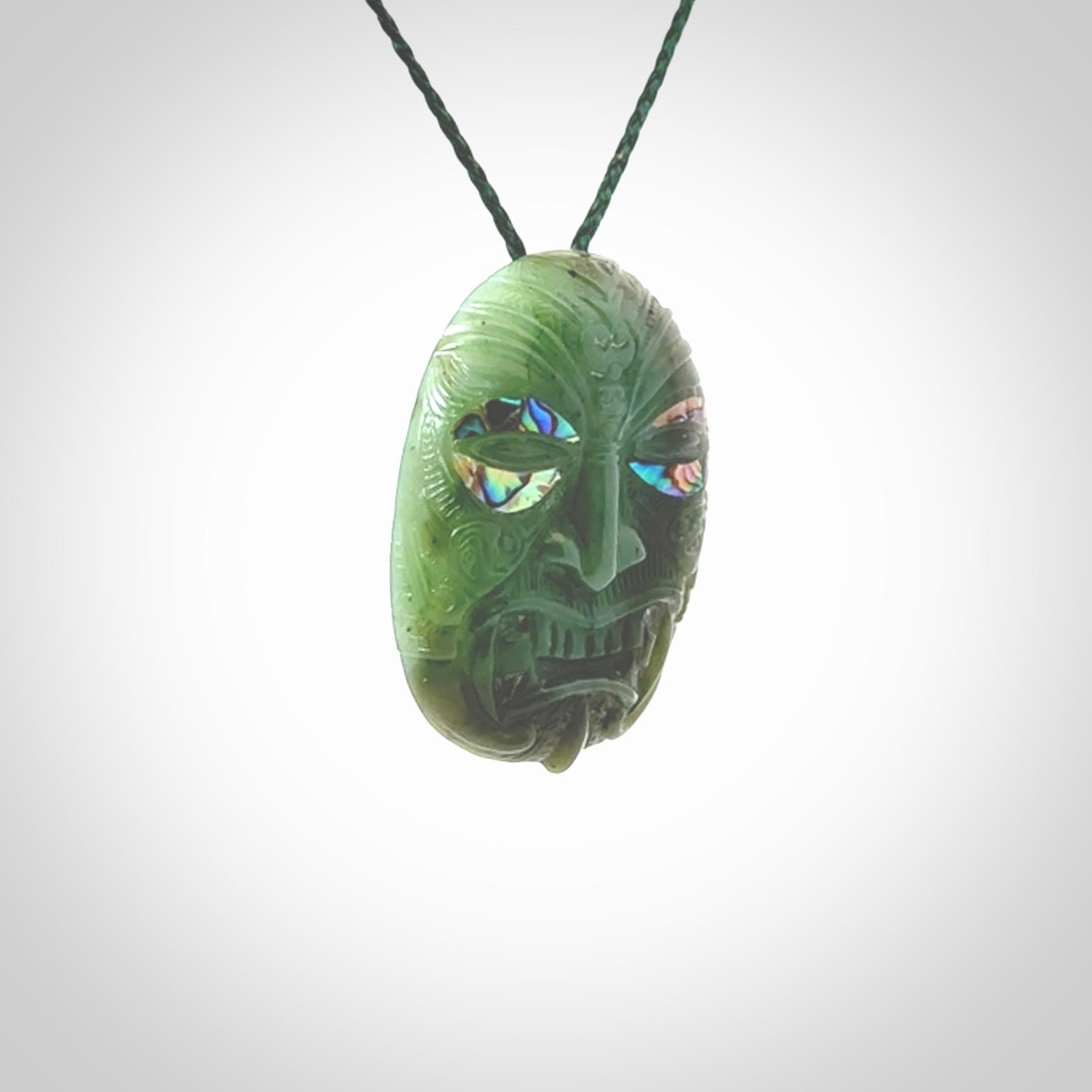 This picture shows a hand carved Jade with paua shell face pendant. It is a varied green colour which is quite beautiful. Although a medium piece, it is a wonderful, delicate piece of jewellery. The cord is hand plaited and adjustable so that you can position the pendant where it suits you best. Delivery is free worldwide.