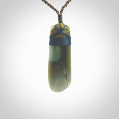 This photo shows a beautiful Inanga jade toki suspended from a hand plaited adjustable cord. The binding around the top of the toki is a blue and khaki green colour. The cord is length adjustable which allows the pendant to be positioned where it suits you best. The toki was carved for us by Jen Hung who is a master jade carver from New Zealand.