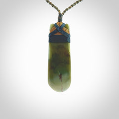 This photo shows a beautiful Inanga jade toki suspended from a hand plaited adjustable cord. The binding around the top of the toki is a blue and brown colour. The cord is length adjustable which allows the pendant to be positioned where it suits you best. The toki was carved for us by Jen Hung who is a wonderful jade carver from New Zealand.