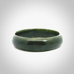 Hand carved jade bangle. Carved from green New Zealand jade. This is a solid jade bangle carved from a single piece of jade. It is polished to a soft shine. The jade is otherwise untreated and completely natural.