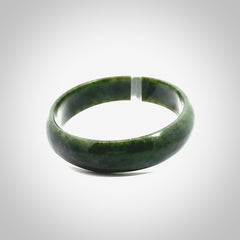 Hand carved jade bangle. Carved from green New Zealand jade. This is a solid jade bangle carved from a single piece of jade. It is polished to a soft shine. The jade is otherwise untreated and completely natural.