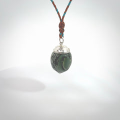 This picture shows a little jade acorn pendant. The cap is sterling silver and is embossed with some decorative markings which give the silver cap some detail and character. Hand made by Ana Krakosky.