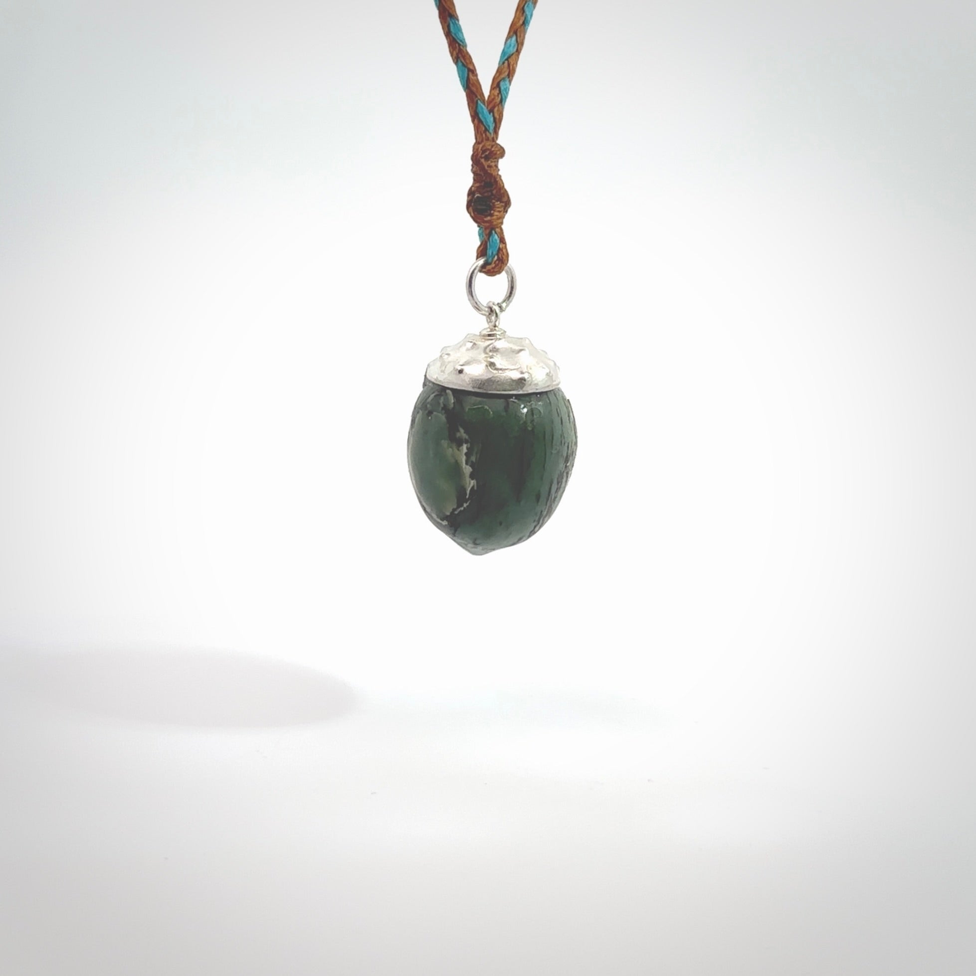 This picture shows a little jade acorn pendant. The cap is sterling silver and is embossed with some decorative markings which give the silver cap some detail and character. Hand made by Ana Krakosky.